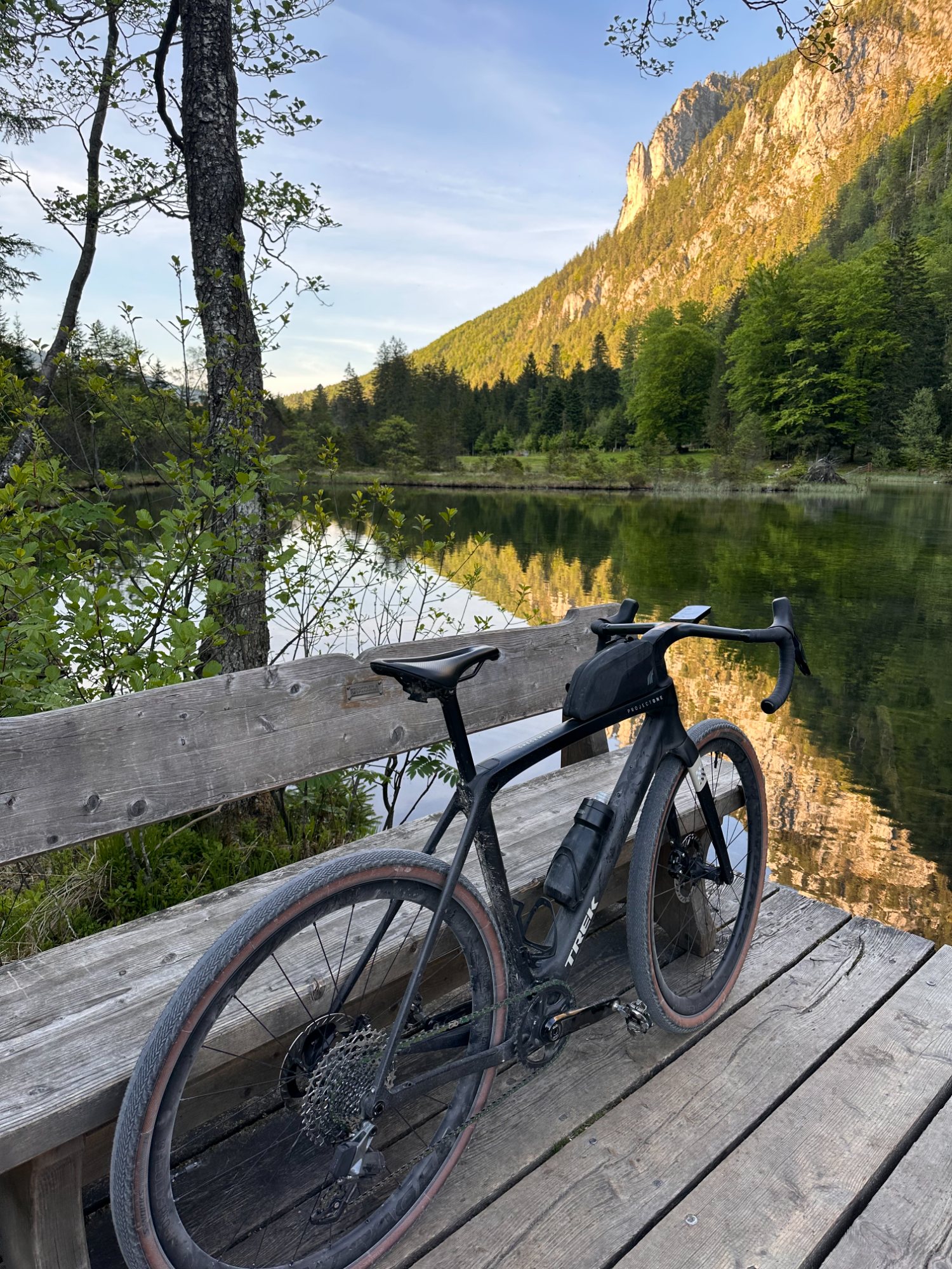Stopp am Falkensee: das Gravelbike am Steg, dahinter spiegelglattes Wasser und die Felswand im warmen Abendlicht.