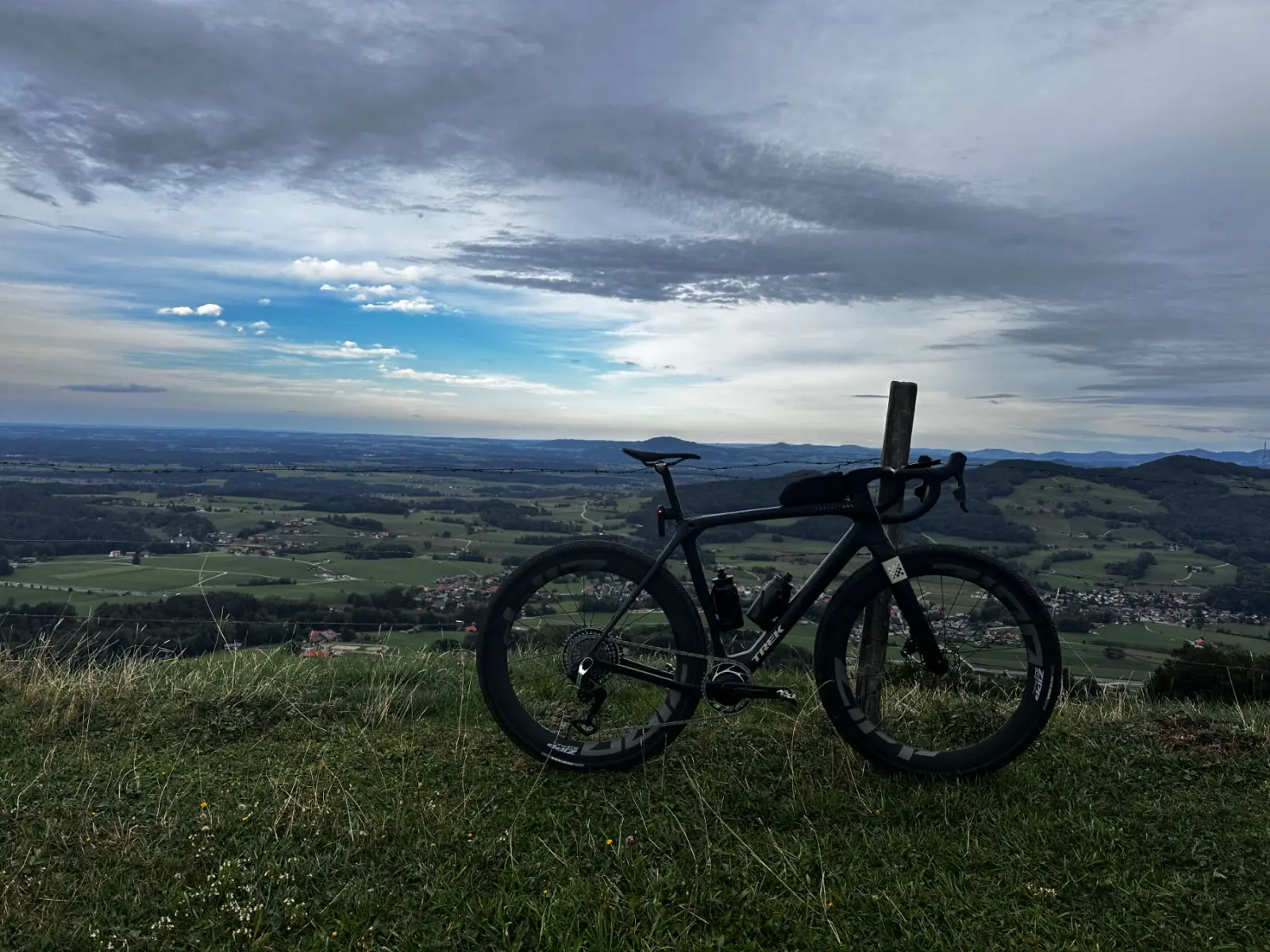 Pause auf der Wiese, unten das weite Alpenvorland unter einem wechselhaften Himmel.